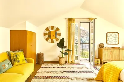 a living room with a yellow couch and a window at Yeotown Madeira Wellness Hotel and Nature Stay in Arco da Calheta