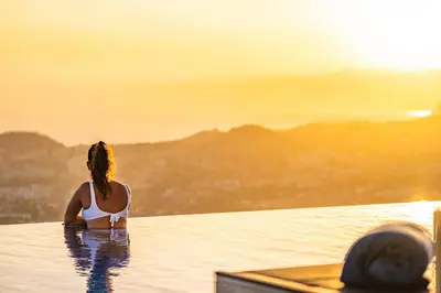 a woman in a infinity pool watching the sunset at Villa Boa Nova Preta by LovelyStay in Funchal