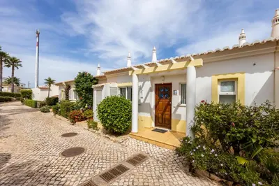 a white house with a wooden door on a street at Townhouse da Amarela in Budens