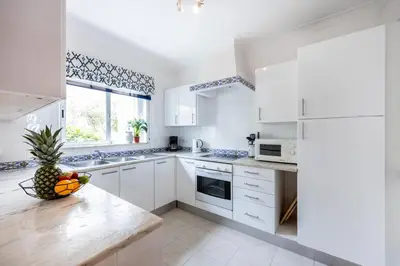 a kitchen with white cabinets and a bowl of fruit on a counter at Townhouse da Amarela in Budens