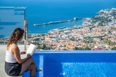 a woman sitting on the edge of a pool reading a book at Villa Boa Nova Branca by LovelyStay in Funchal