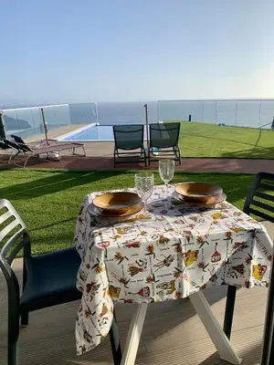 a table with glasses and plates on it with a view of the ocean at Madeira Sea Sunshine with heated pool in Ribeira Brava