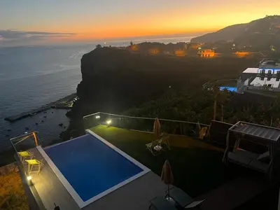 a house with a swimming pool next to the ocean at Madeira Sea Sunshine with heated pool in Ribeira Brava