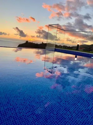 a swimming pool with a sunset in the background at Madeira Sea Sunshine with heated pool in Ribeira Brava