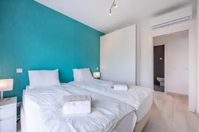 a large white bed in a room with a green wall at Villa Sagres Surf in Sagres