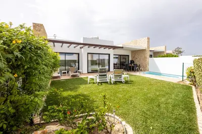 a house with a yard with chairs and a swimming pool at Villa Sagres Surf in Sagres