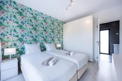 a bedroom with a large bed with a floral wallpaper at Villa Sagres Surf in Sagres