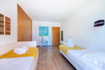 two beds in a room with white walls and wooden floors at Villa Cercado, private swimming pool in Sagres