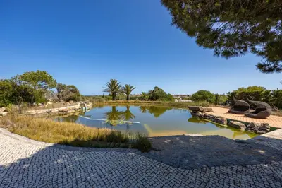 a pond in a park with benches and trees at Villa Cercado, private swimming pool in Sagres