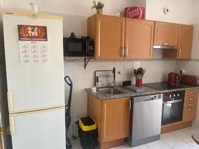 a kitchen with wooden cabinets and a white refrigerator at Central Park Sea Views in Santa Cruz