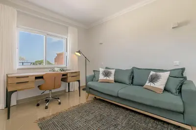 a living room with a couch and a desk and a window at Casa Makin at Boa Vista Golf Resort, Bayview Village in Lagos