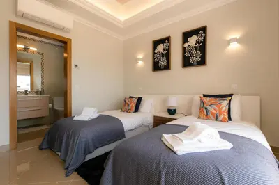 two beds in a room with a bathroom at Casa Makin at Boa Vista Golf Resort, Bayview Village in Lagos