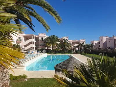 a swimming pool with palm trees and buildings at Top-floor 2 BR holiday home with sea view and pool in Luz