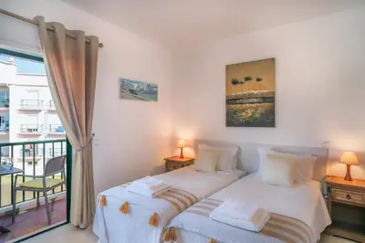 a bedroom with two beds and a balcony at Top-floor 2 BR holiday home with sea view and pool in Luz