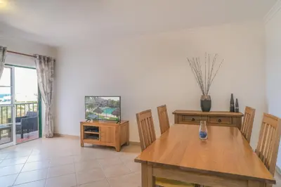 a dining room with a table and a television at Top-floor 2 BR holiday home with sea view and pool in Luz