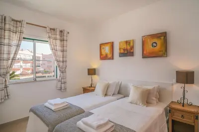 a bedroom with two beds and a window at Top-floor 2 BR holiday home with sea view and pool in Luz
