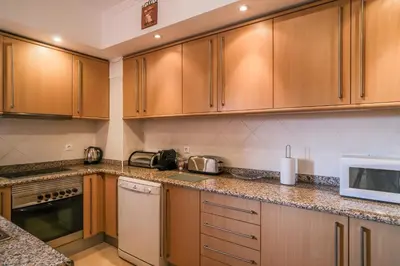 a kitchen with wooden cabinets and a microwave at Top-floor 2 BR holiday home with sea view and pool in Luz