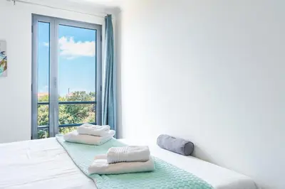 a white bedroom with a window with towels on a bed at Vista Mar by Atlantic Holiday in Caniço