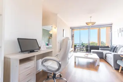 a living room with a desk with a tv and a chair at Vista Mar by Atlantic Holiday in Caniço