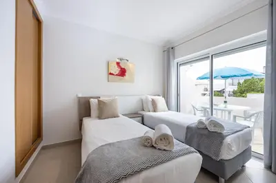 two beds in a room with a table and a window at IM On Casa Mar e SOL in Lagos