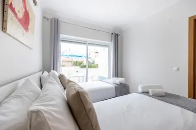 a white room with two beds and a window at IM On Casa Mar e SOL in Lagos