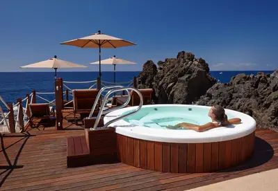 a woman laying in a hot tub on a deck at La Villa at The Cliff Bay - PortoBay in Funchal