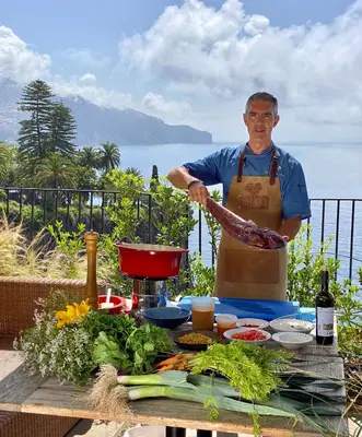 a man standing next to a table of food at La Villa at The Cliff Bay - PortoBay in Funchal