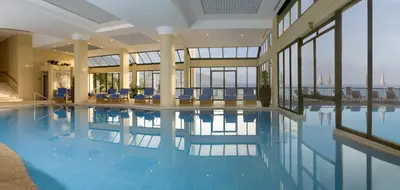 a swimming pool with blue chairs in a building at La Villa at The Cliff Bay - PortoBay in Funchal
