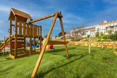 a wooden swing set on the grass in a yard at Casa Monte Salema in Vila do Bispo