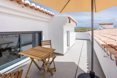 a wooden table on a balcony with an umbrella at Casa Monte Salema in Vila do Bispo