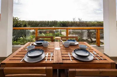 a wooden table with plates and utensils on a balcony at Casa Monte Salema in Vila do Bispo