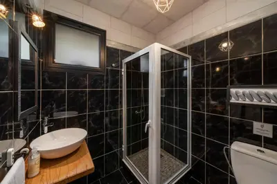 a black tiled bathroom with a sink and a shower at Casa de Campo Arco de São Jorge by An Island Apart in Santana