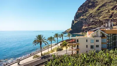 a building on the beach with palm trees and the ocean at Sunny Side by Atlantic Holiday in Madalena do Mar