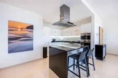 a kitchen with white cabinets and a black island with stools at CoolHouses Algarve Lagos, 3 Bed modern Flat, outdoor & Indoor pools, Gym, Amor à Vida in Lagos