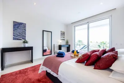 a bedroom with a large bed with red pillows at CoolHouses Algarve Lagos, 3 Bed modern Flat, outdoor & Indoor pools, Gym, Amor à Vida in Lagos