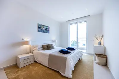 a white bedroom with a bed and a large window at CoolHouses Algarve Lagos, 3 Bed modern Flat, outdoor & Indoor pools, Gym, Amor à Vida in Lagos