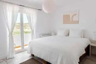 a white bedroom with a bed and a large window at Casa Almargens in Aljezur by Lisbeyond in Bordeira