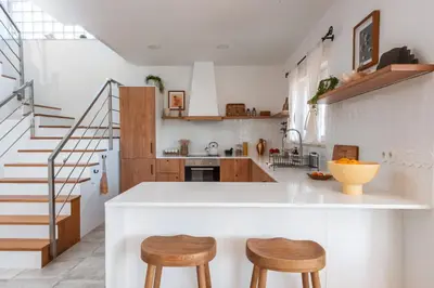 a kitchen with a white counter and two wooden stools at Casa Almargens in Aljezur by Lisbeyond in Bordeira