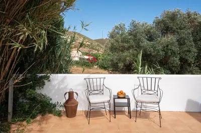 two chairs and a table with a vase on a patio at Casa Almargens in Aljezur by Lisbeyond in Bordeira