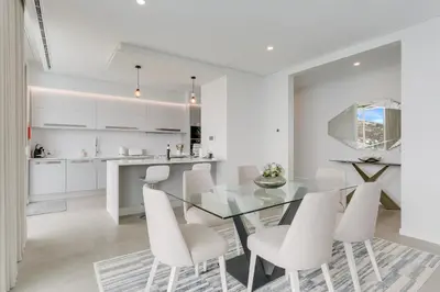 a kitchen and dining room with a glass table and white chairs at Luxury Villa Bianca by Holiday Rental Madeira in Arco da Calheta