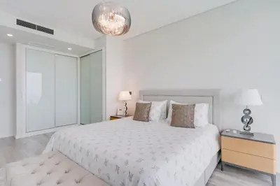 a white bedroom with a large bed and a lamp at Luxury Villa Bianca by Holiday Rental Madeira in Arco da Calheta