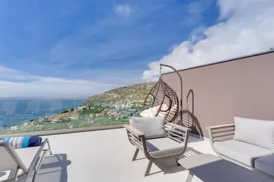 a balcony with chairs and a view of a city at Luxury Villa Bianca by Holiday Rental Madeira in Arco da Calheta
