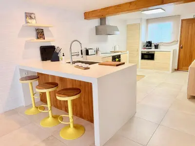 a kitchen with a white counter and wooden stools at Casa da Pedreira in Porto Santo