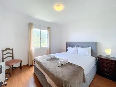 a bedroom with a bed with a chair and a window at Casa do Romaninho in Porto da Cruz
