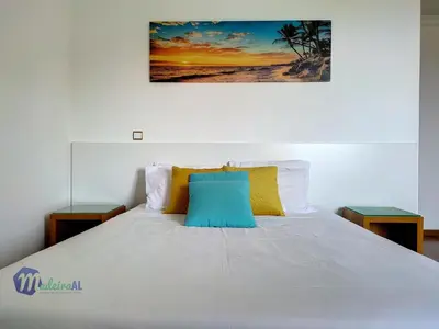 a bed with a blue pillow on top of it at Yohanna's accommodation in Campanário