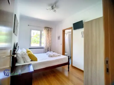 a bedroom with a bed with white sheets and yellow pillows at Yohanna's accommodation in Campanário