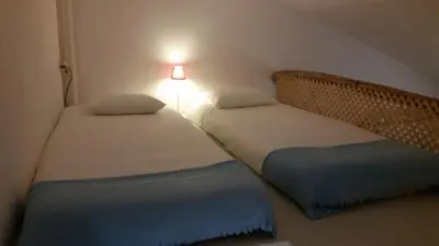 two twin beds in a small room with a lamp at PuraVida Divehouse in Sagres