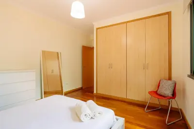 a bedroom with a white bed and a red chair at Ponta do Sol Amazing 3 Bedroom Apartment in Ponta do Sol