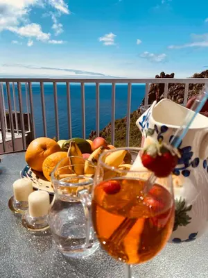 a table with a bowl of fruit and glasses on a balcony at Villa Sophia by ALMA Holiday Rentals in Caniço