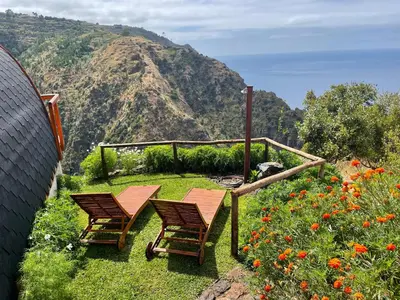 two chairs and a table with a view of a mountain at The tiny black bird in Fajã da Ovelha